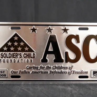 Silver decorative license plate with ASCF logo and motto in black letters.